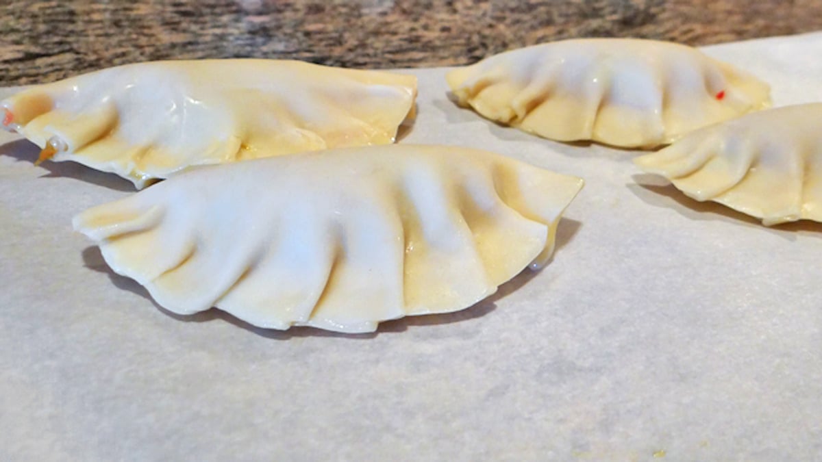 Four Asian Style Potstickers are sitting on a baking sheet.