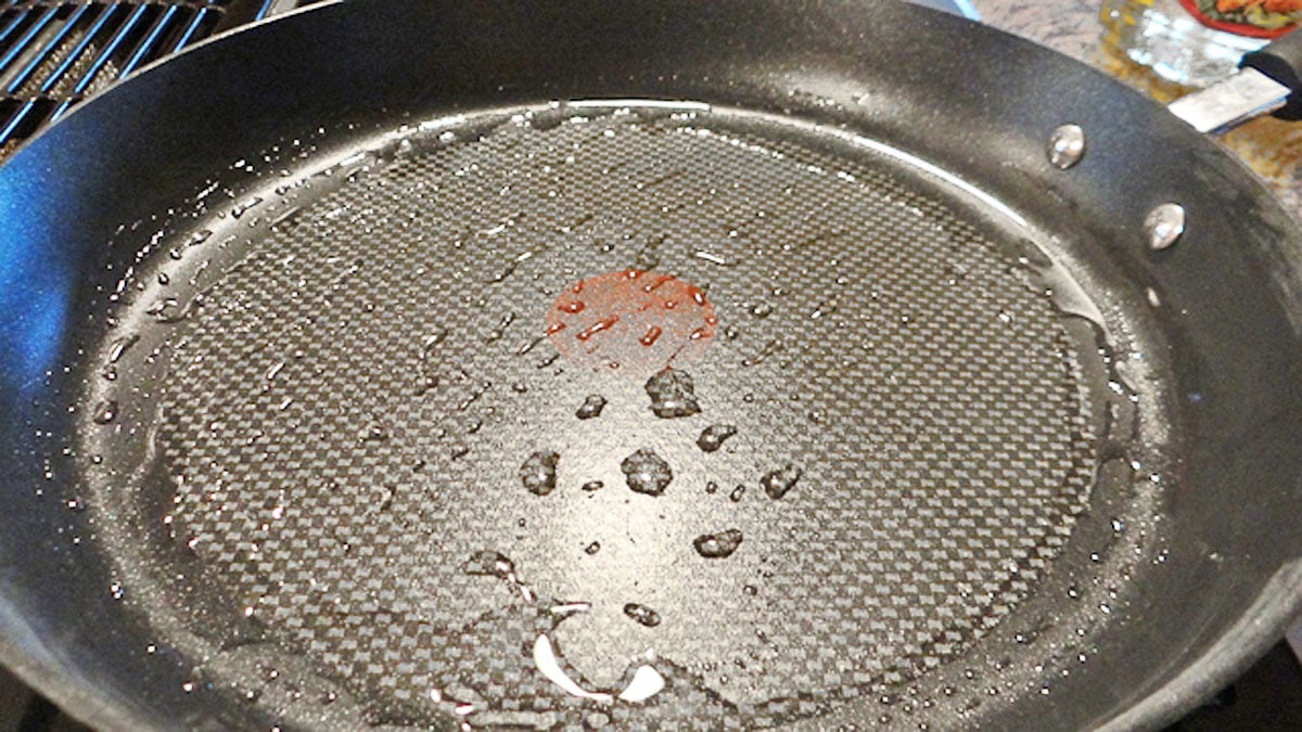 Oil sizzling in a frying pan on a stove.