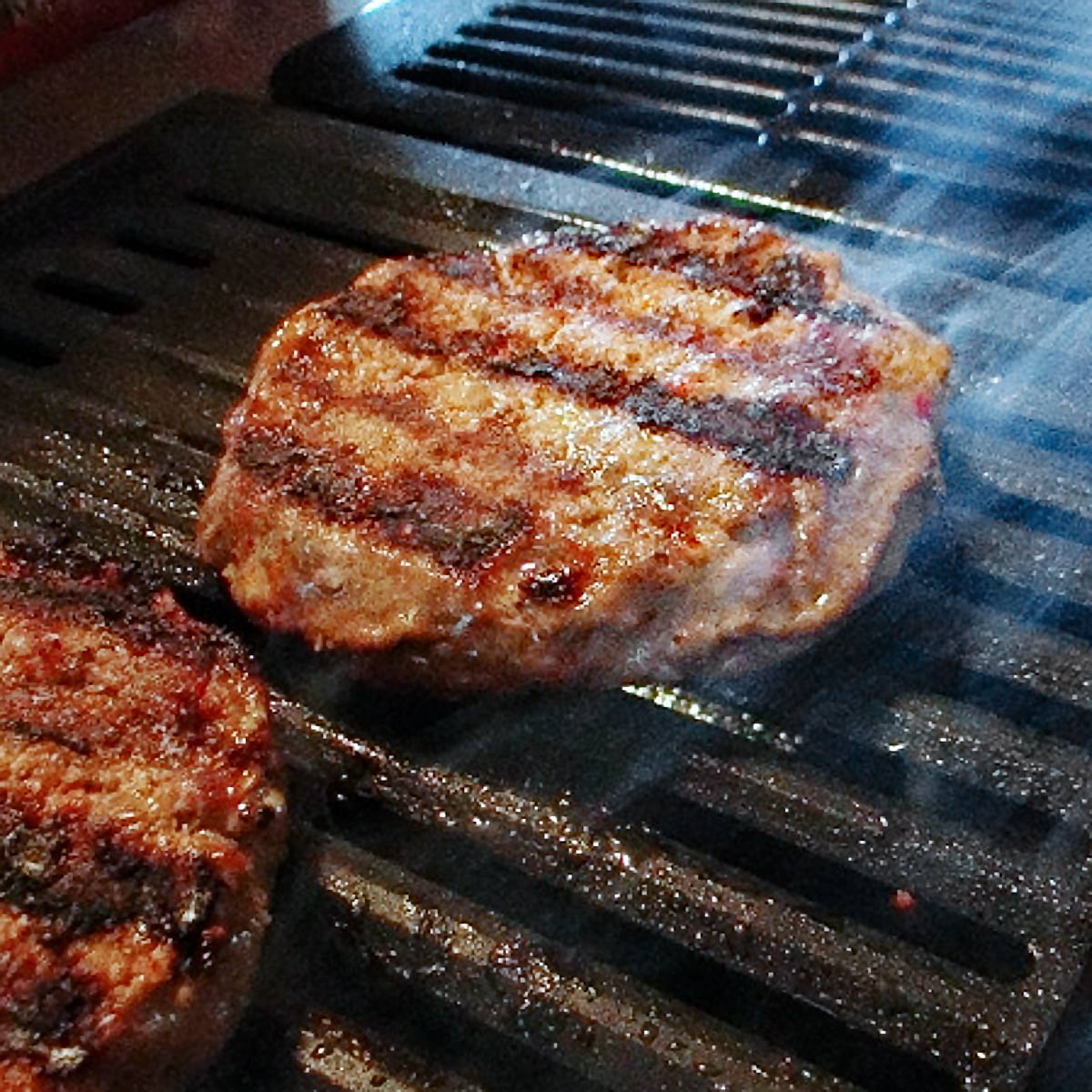 Hamburger patties cooking on a grill.