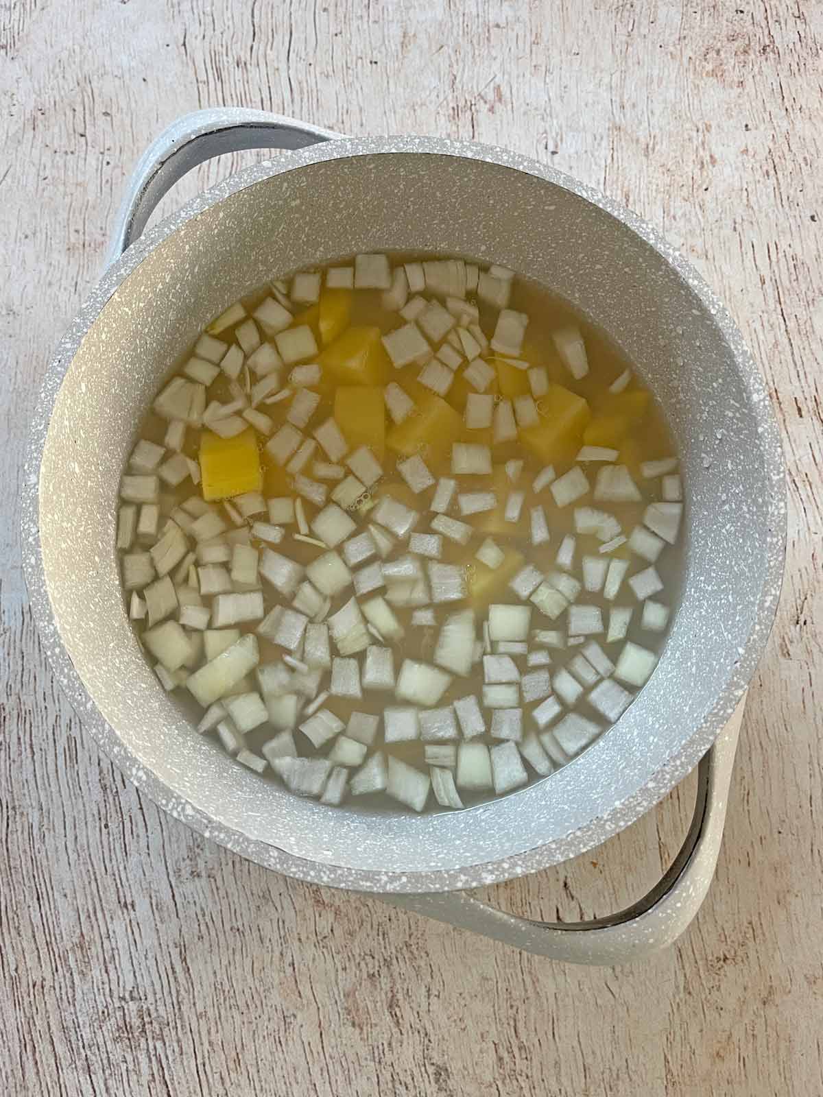 Potatoes and onions added to saucepan.