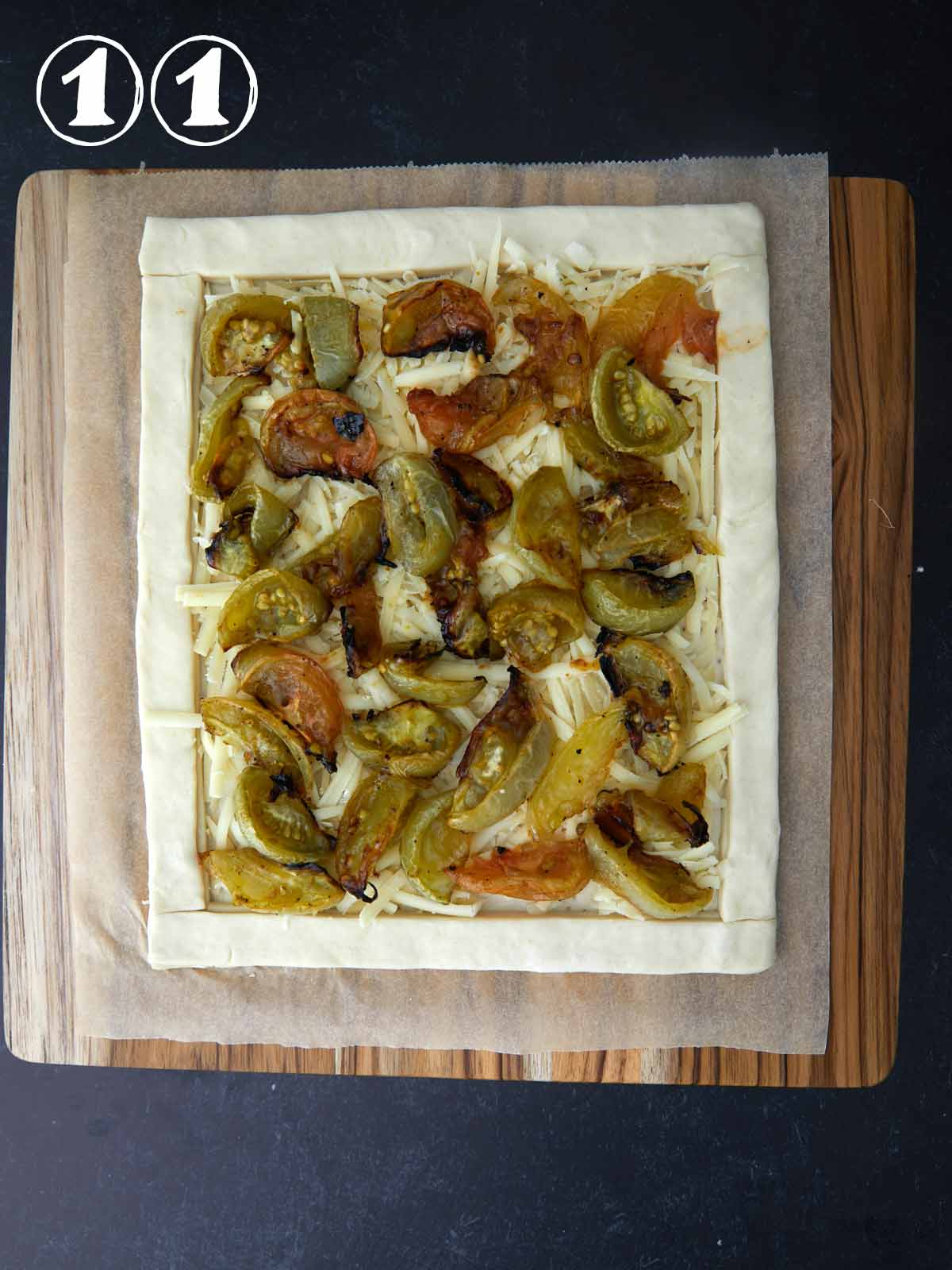 A savory tart topped with green tomatoes on a rustic wooden cutting board.