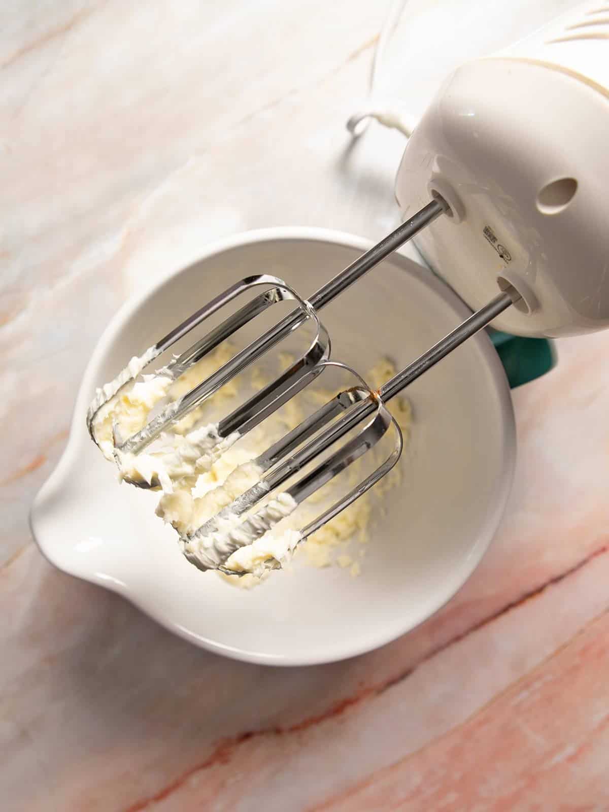 Hand mixer with bowl of whipped butter.
