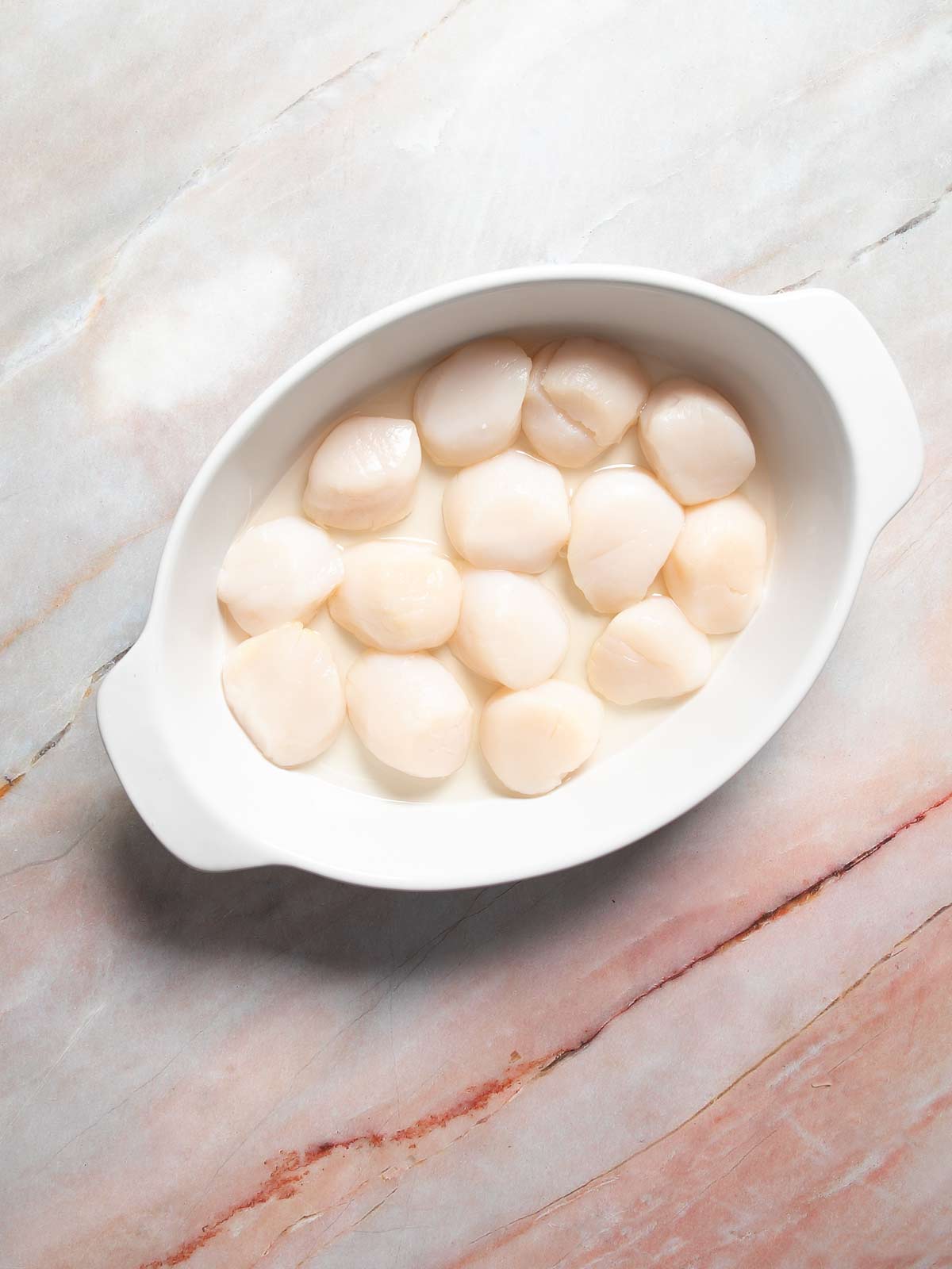 Scallops in single layer in baking dish.
