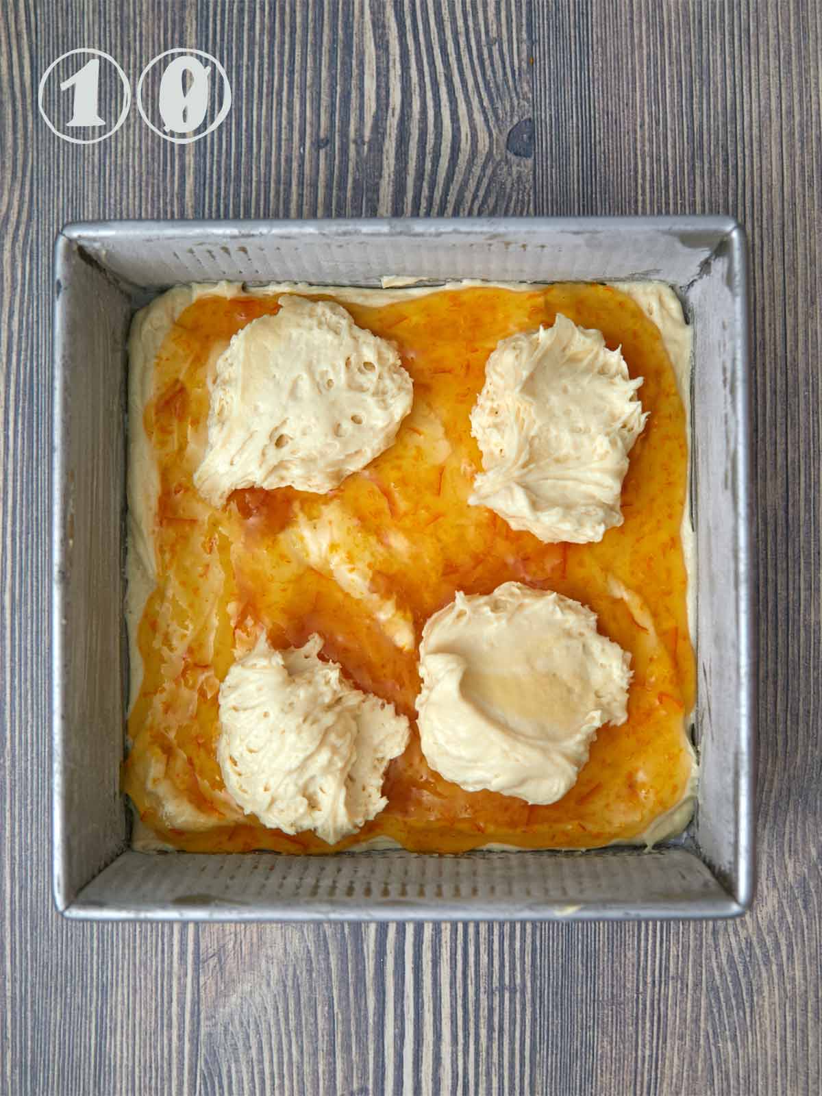 Marmalade spread on the top of the first layer of batter with dollops of the second half of the batter.