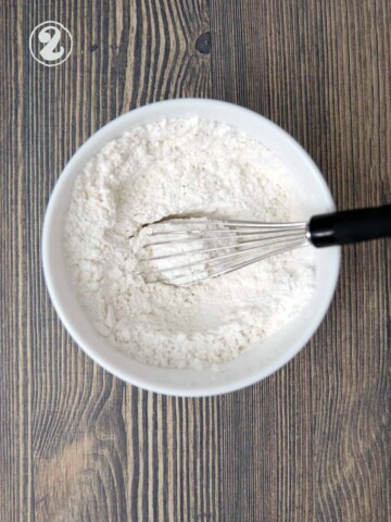 Mixing bowl with flour, salt and baking powder with a whisk.