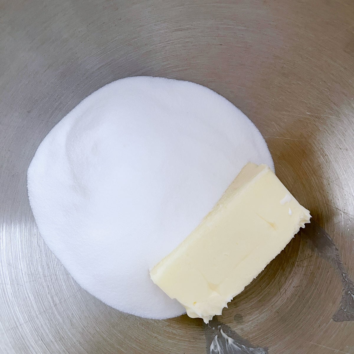 Metal mixer bowl with sugar and butter.