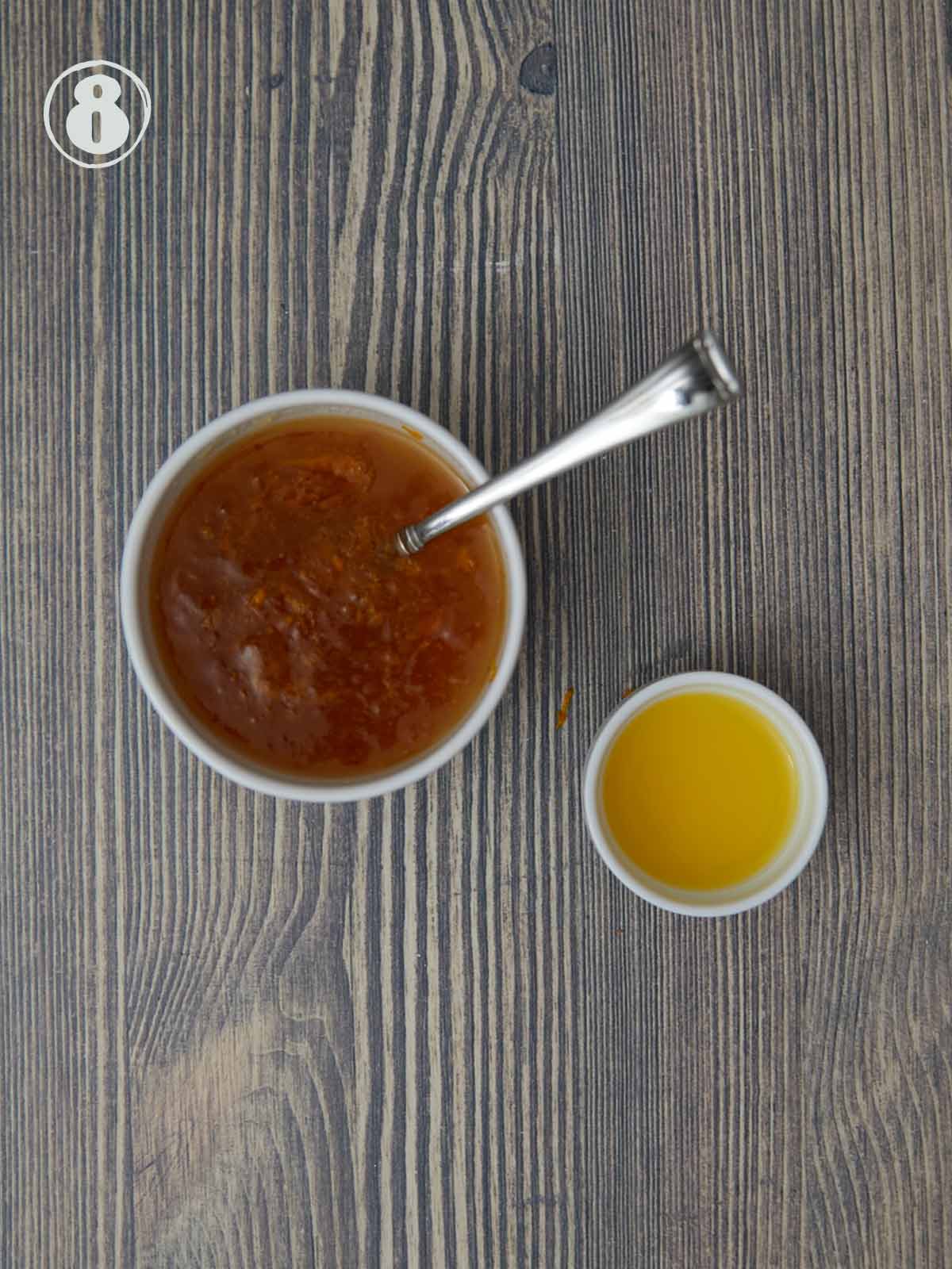 Small bowl of orange marmalade next to a smaller bowl of orange juice.