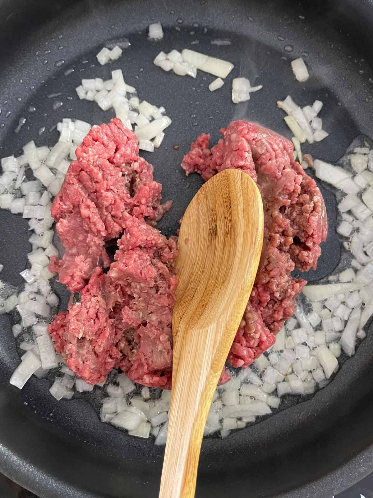 Cooked onions with ground beef added to skilliet.