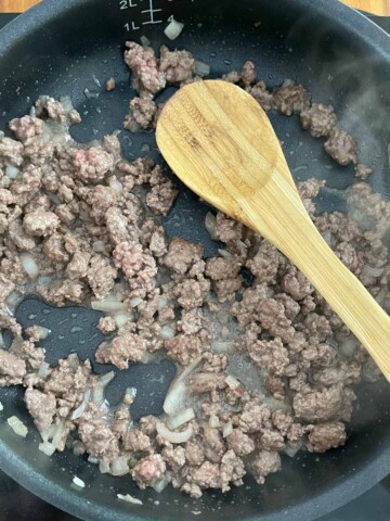 Skillet with browned ground beef and onions.