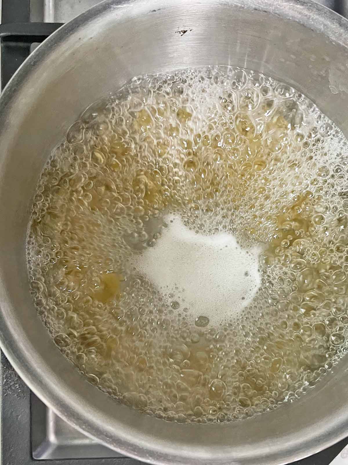 Pot with boiling water and macaroni.