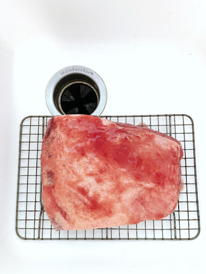 Corned beef on wire rack in sink.