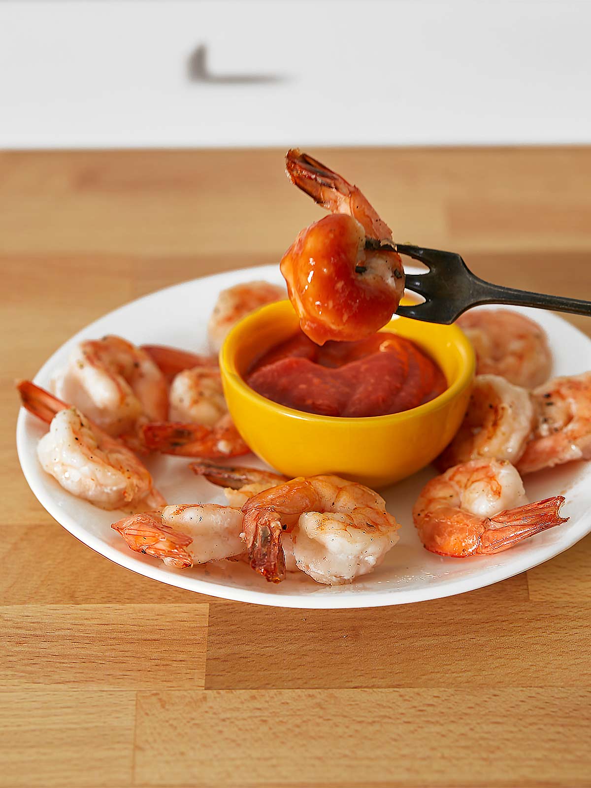Roasted shrimp cocktail on a white plate  with small fork.