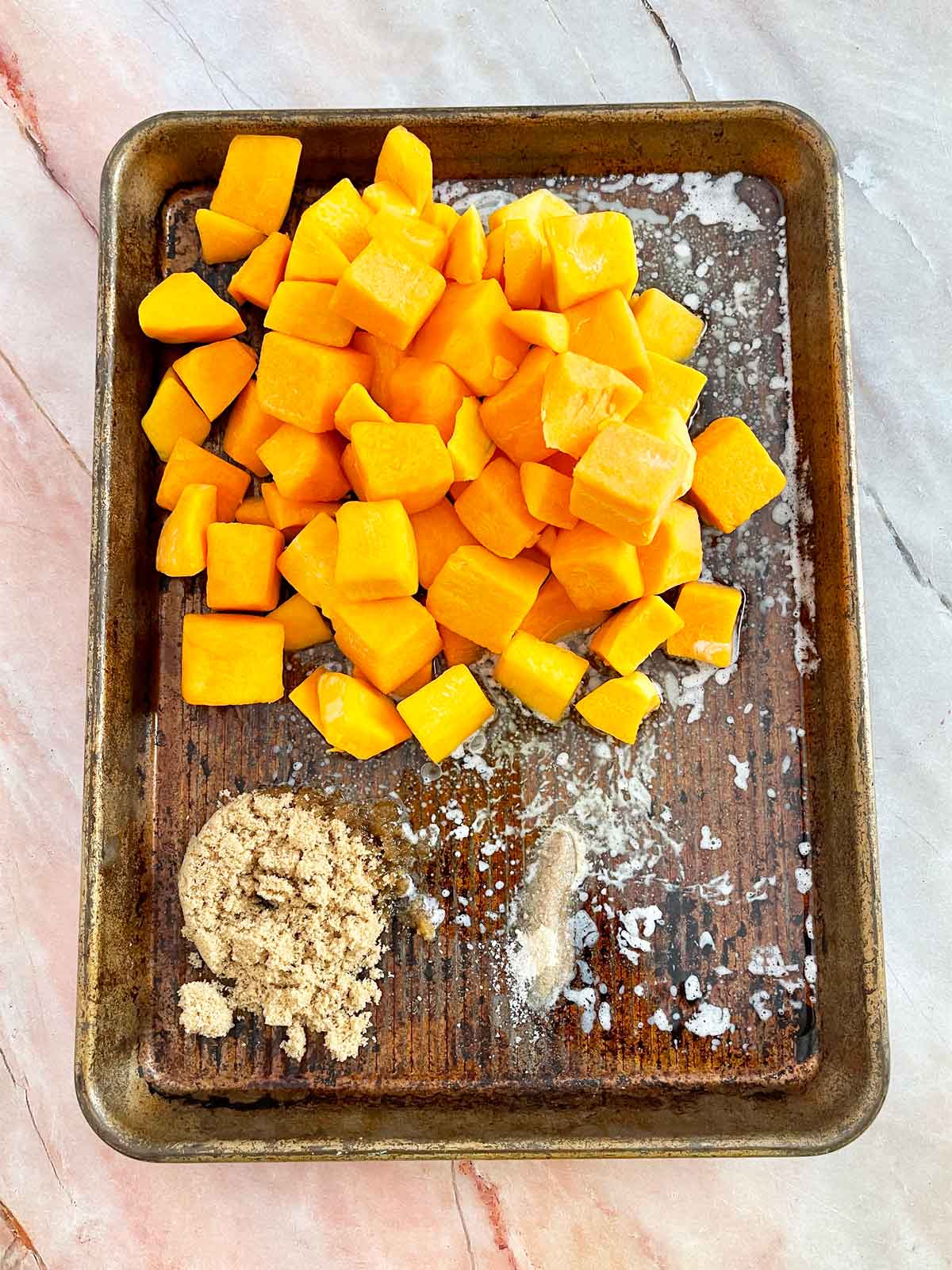 Baking sheet with squash, melted butter, brown sugar, and salt and pepper.