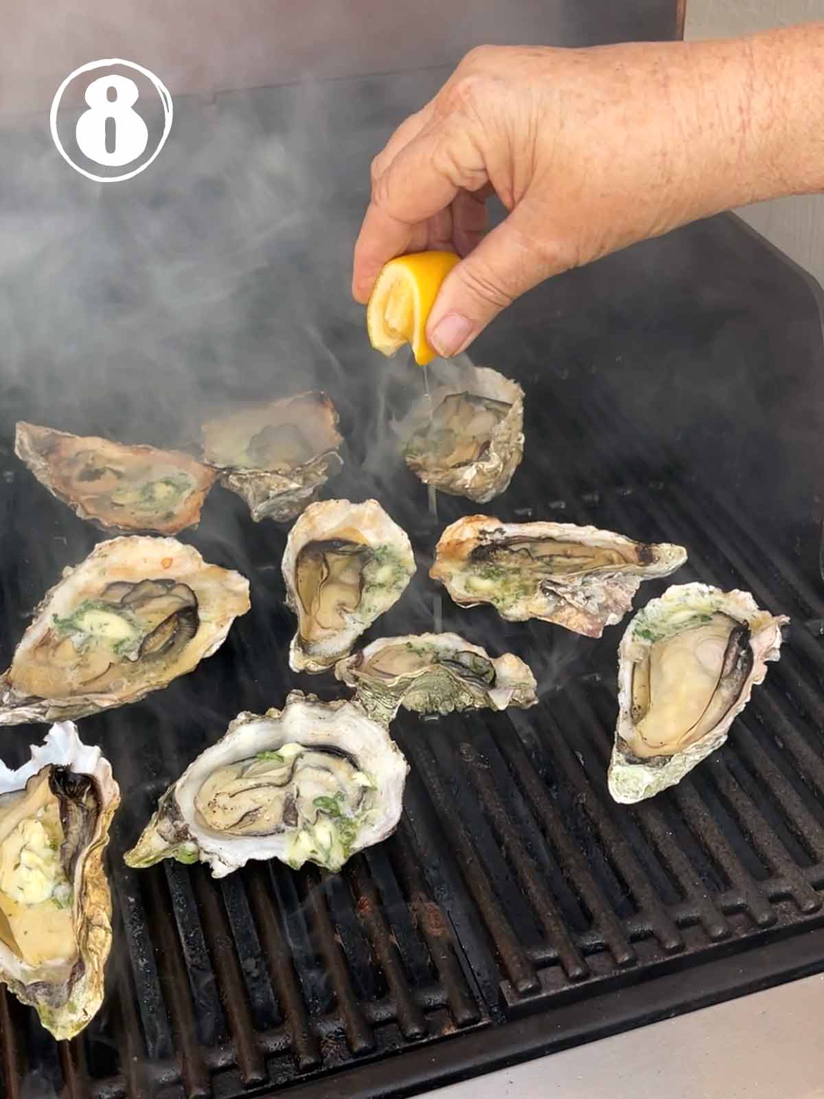 Person squeezing lemon juice over oysters on the grill.