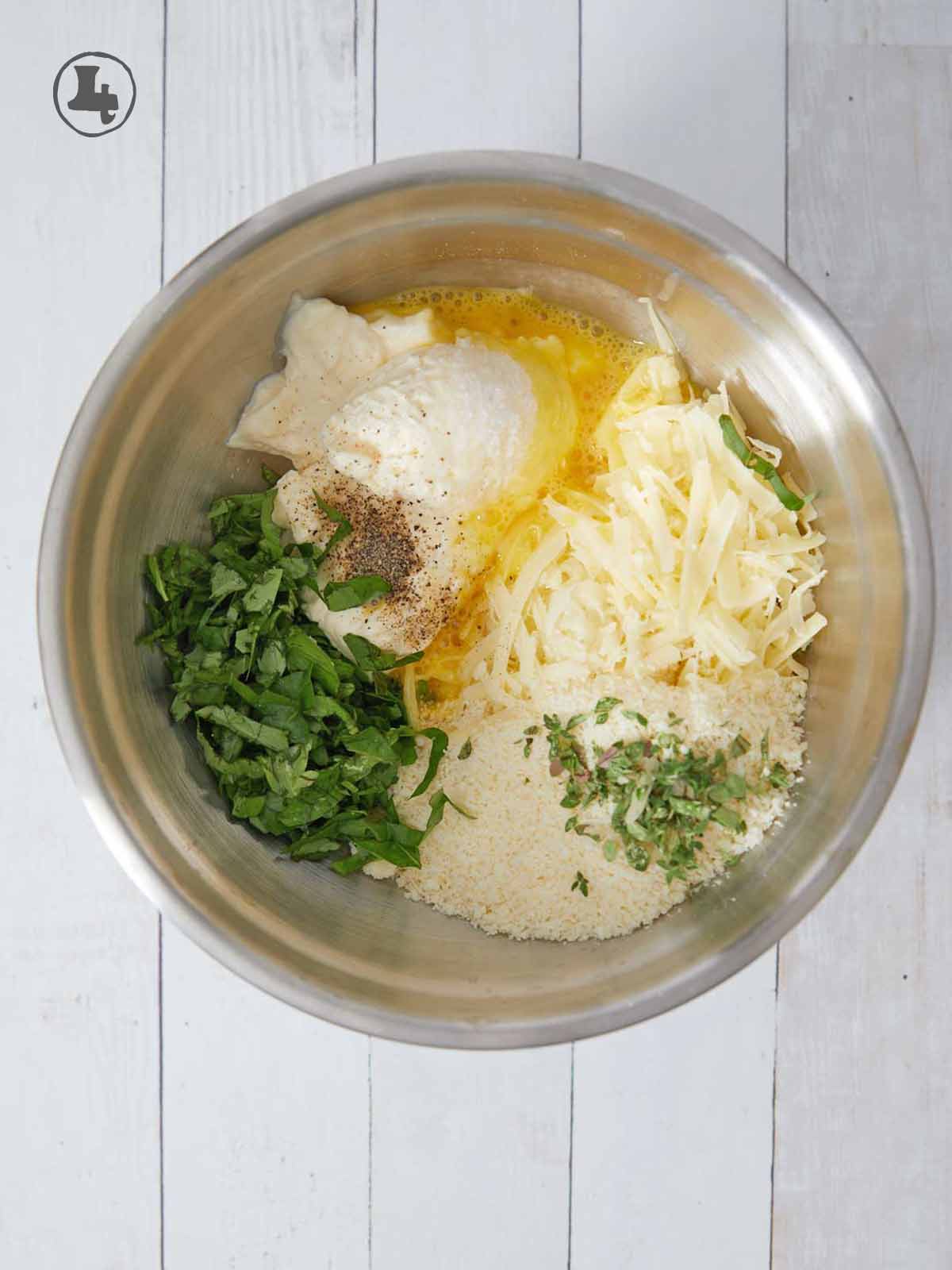Bowl with cheeses, herbs, and an egg.