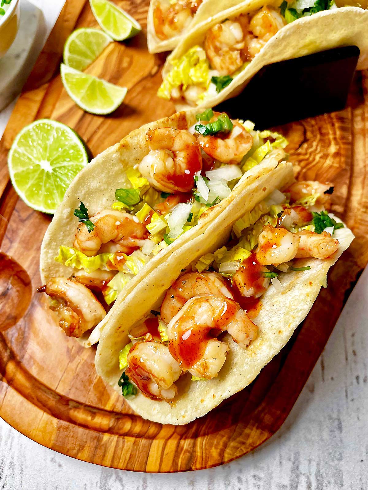 Wooden board with four Spicy Korean BBQ Shrimp Tacos.
