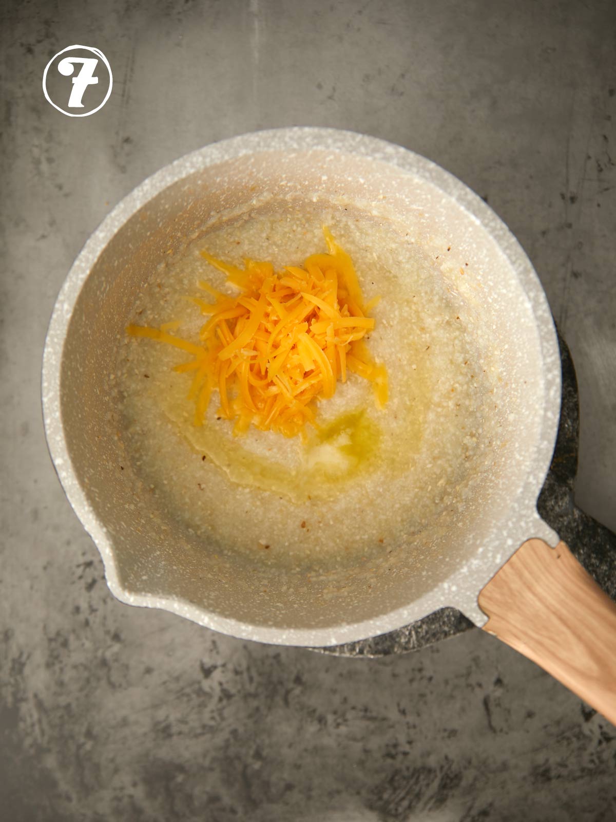 Cheese and butter added to grits cooking in a pot.