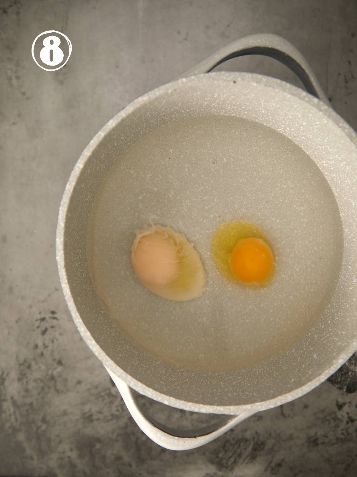 2 eggs poaching in a pot of simmering water.
