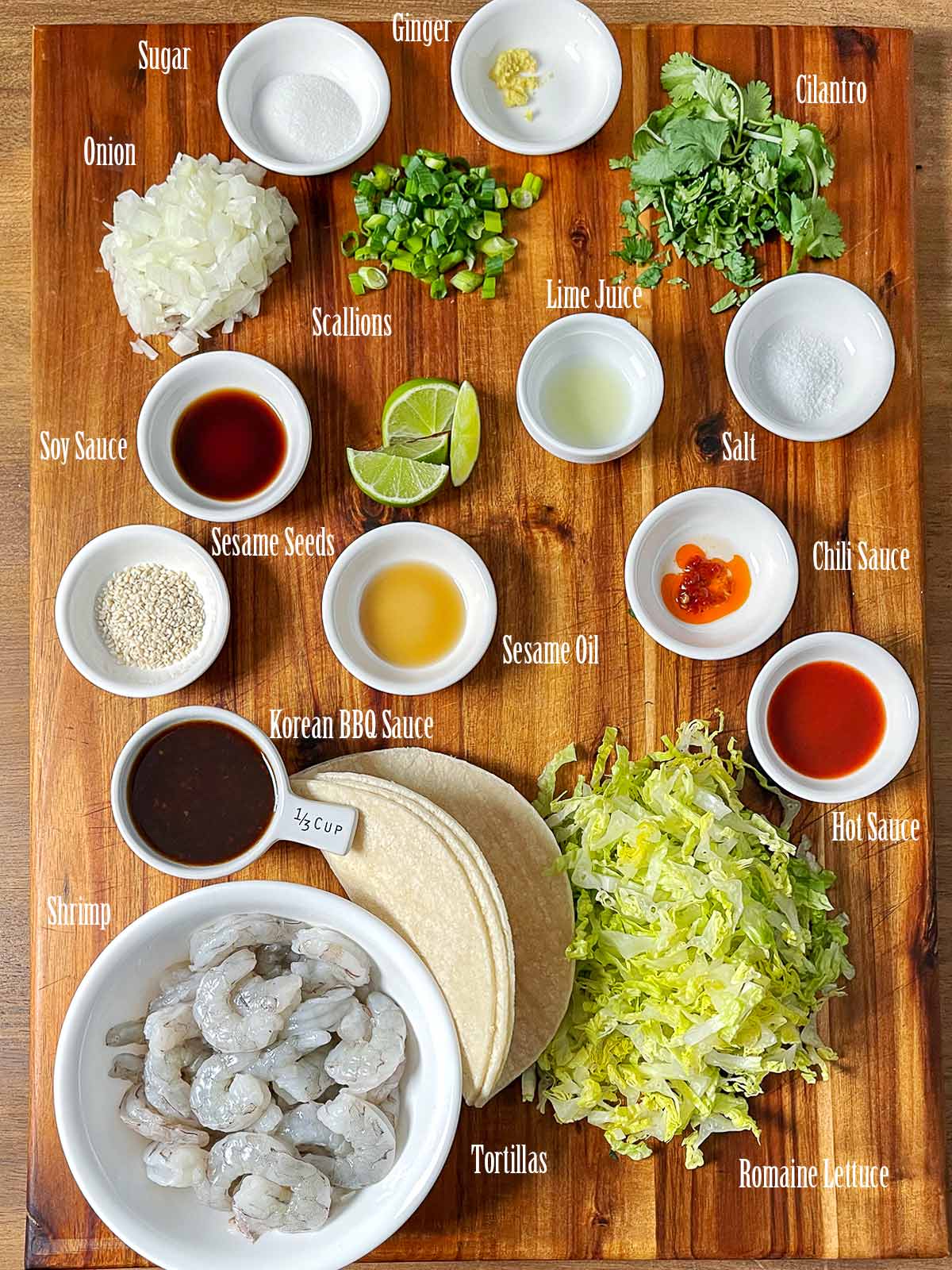 All the ingredients for Spicy Korean BBQ Shrimp Tacos on a wooden cutting board.