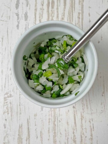 Small bowl with finely diced onion, cilantro, scallions and salt mixed up.