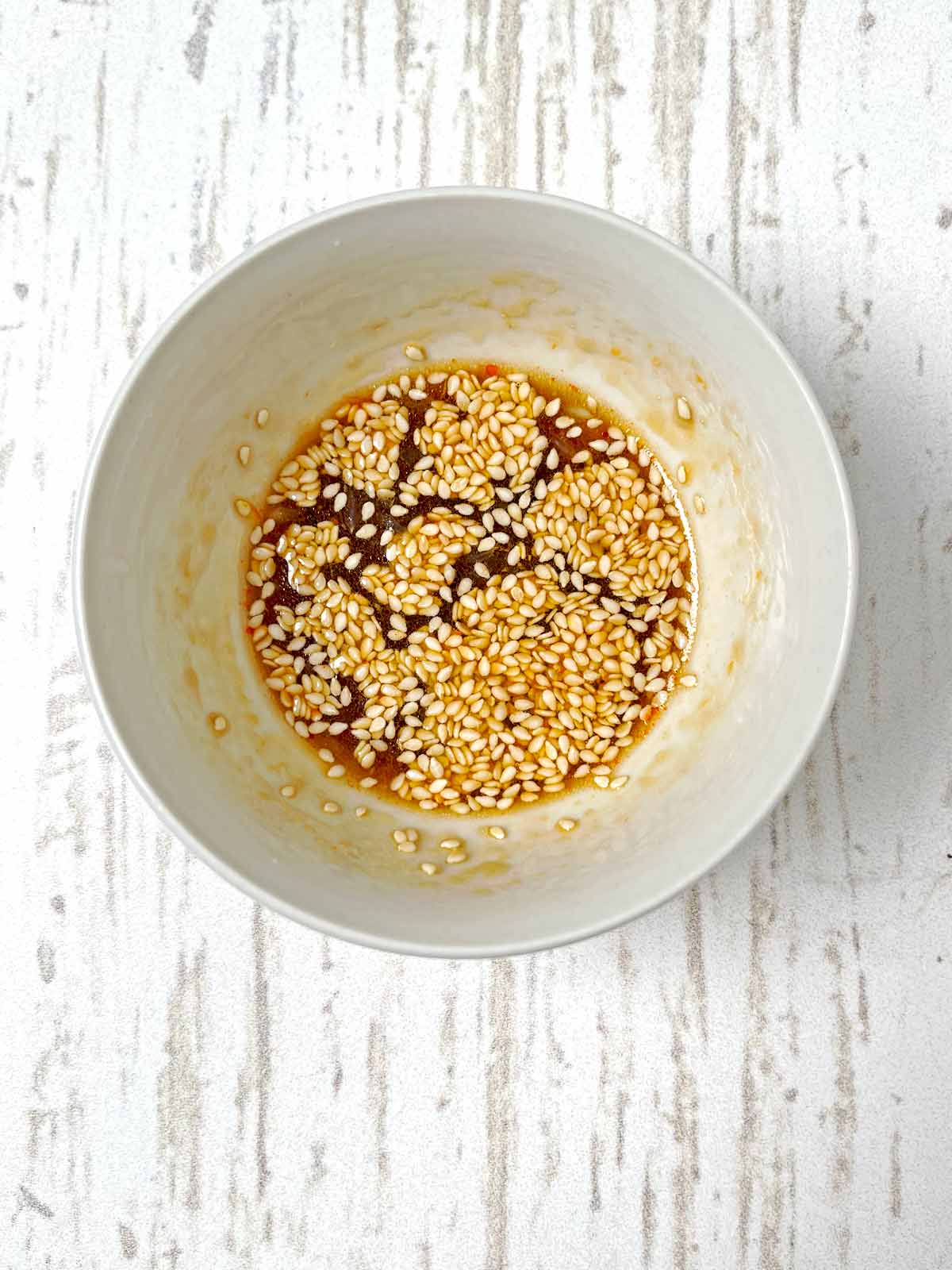 Dressing all mixed up in the bowl with sesame seeds floating on top.