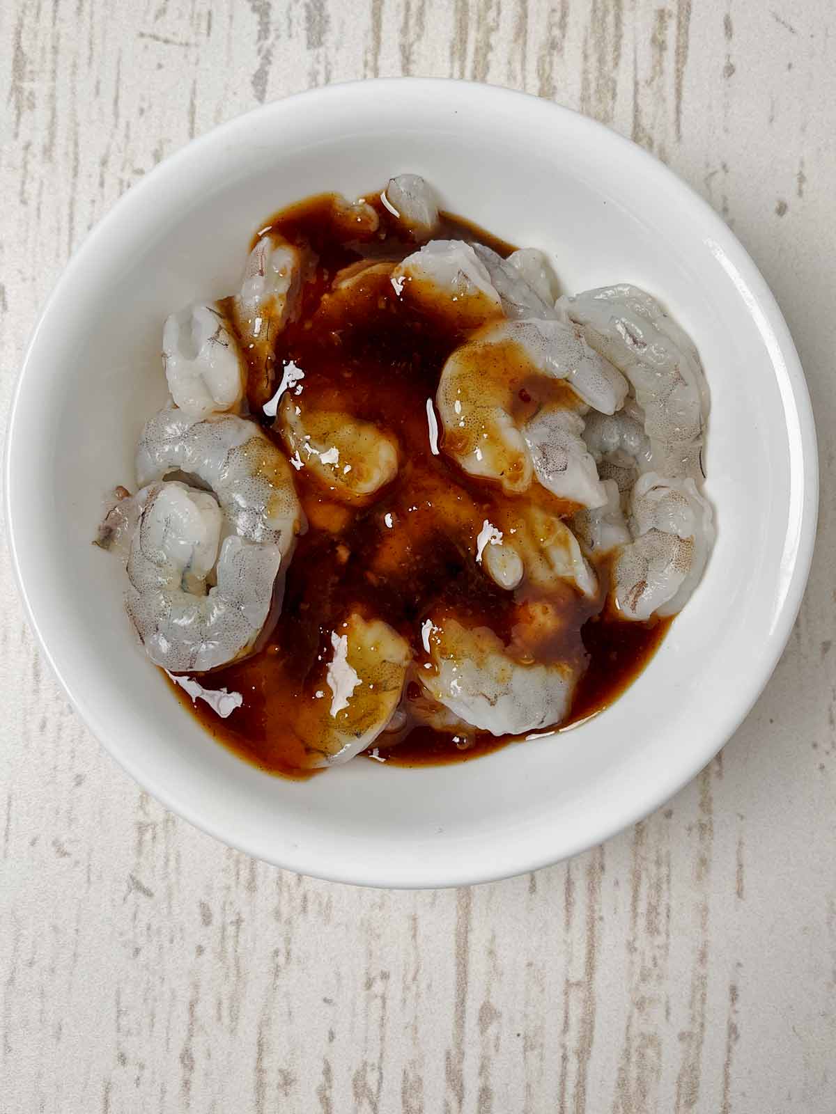 Cleaned shrimp in a bowl with Korean BBQ sauce pored on.