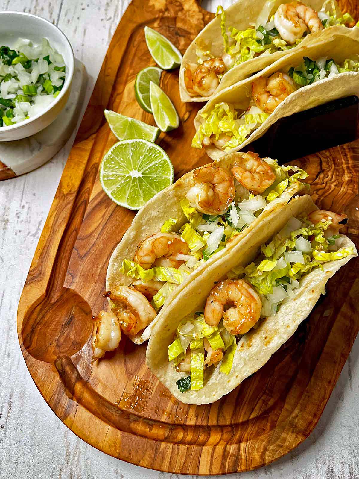 Picture of assembled Spicy Korean BBQ Shrimp Tacos on a wooden board.