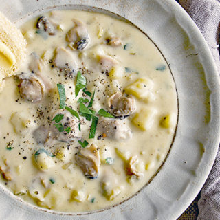 Bowl of clam chowder with potatoes and parsley.