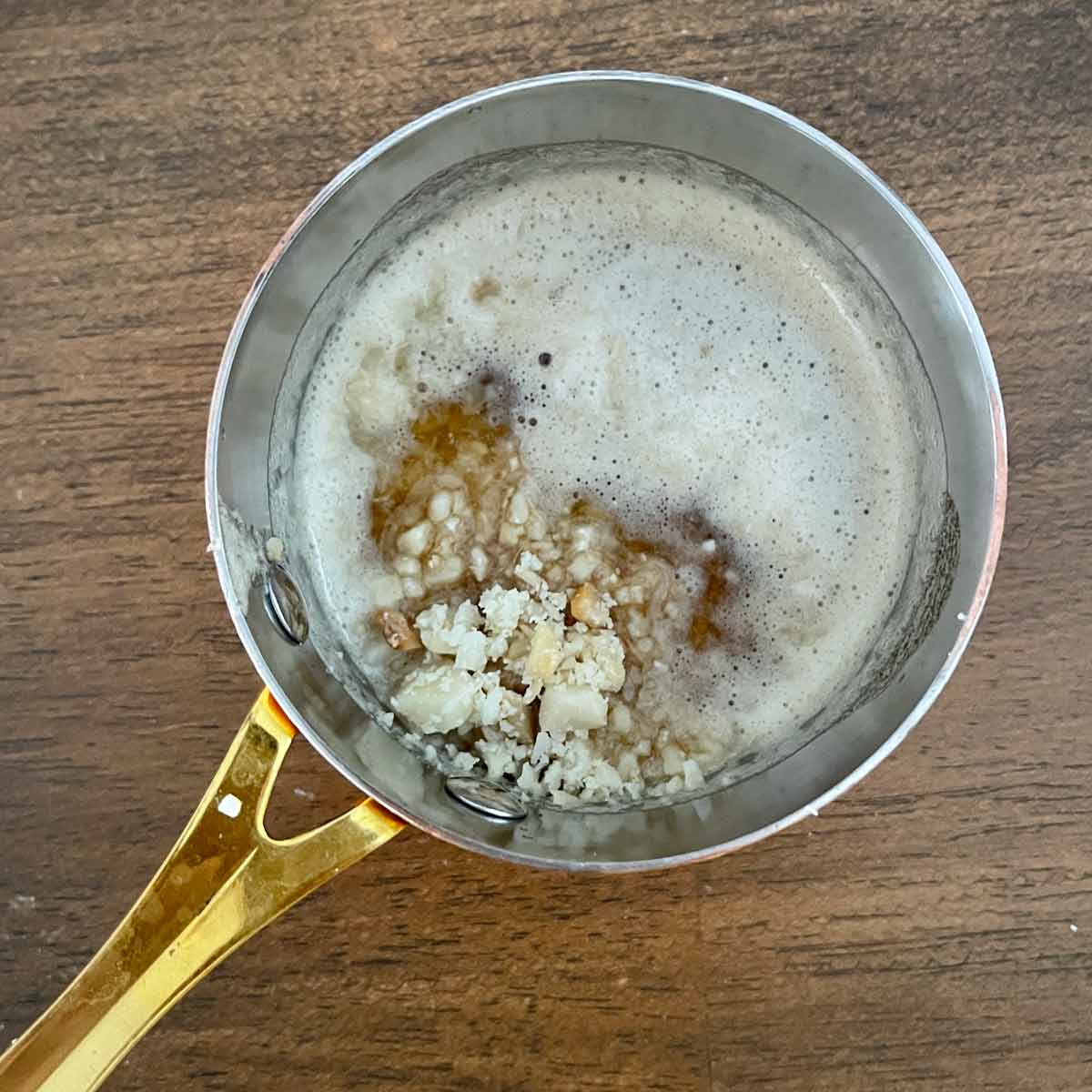 Small saucepot with brown butter and chopped macadamia nuts.