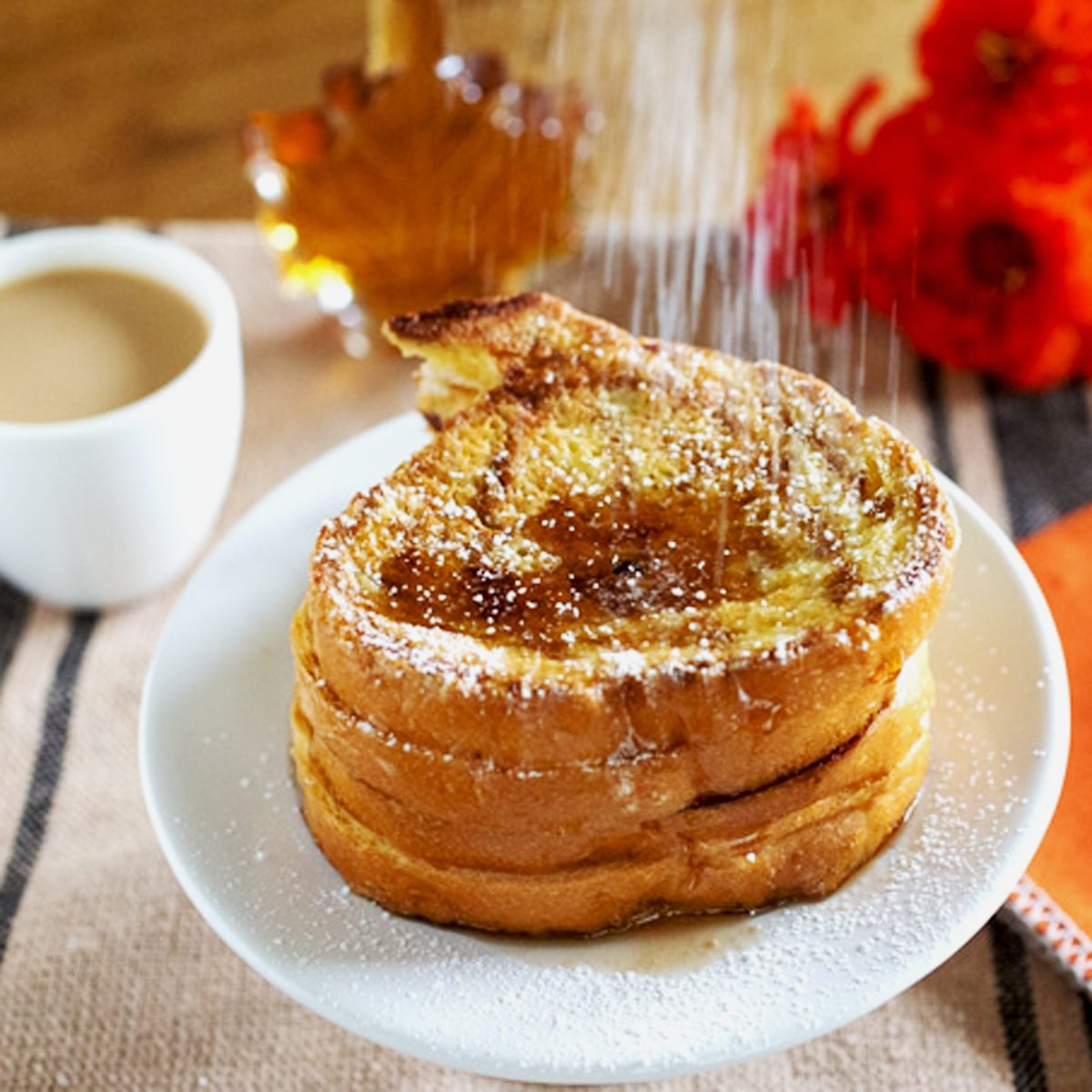 Pumpkin shaped French toast being dusted with powdered sugar.