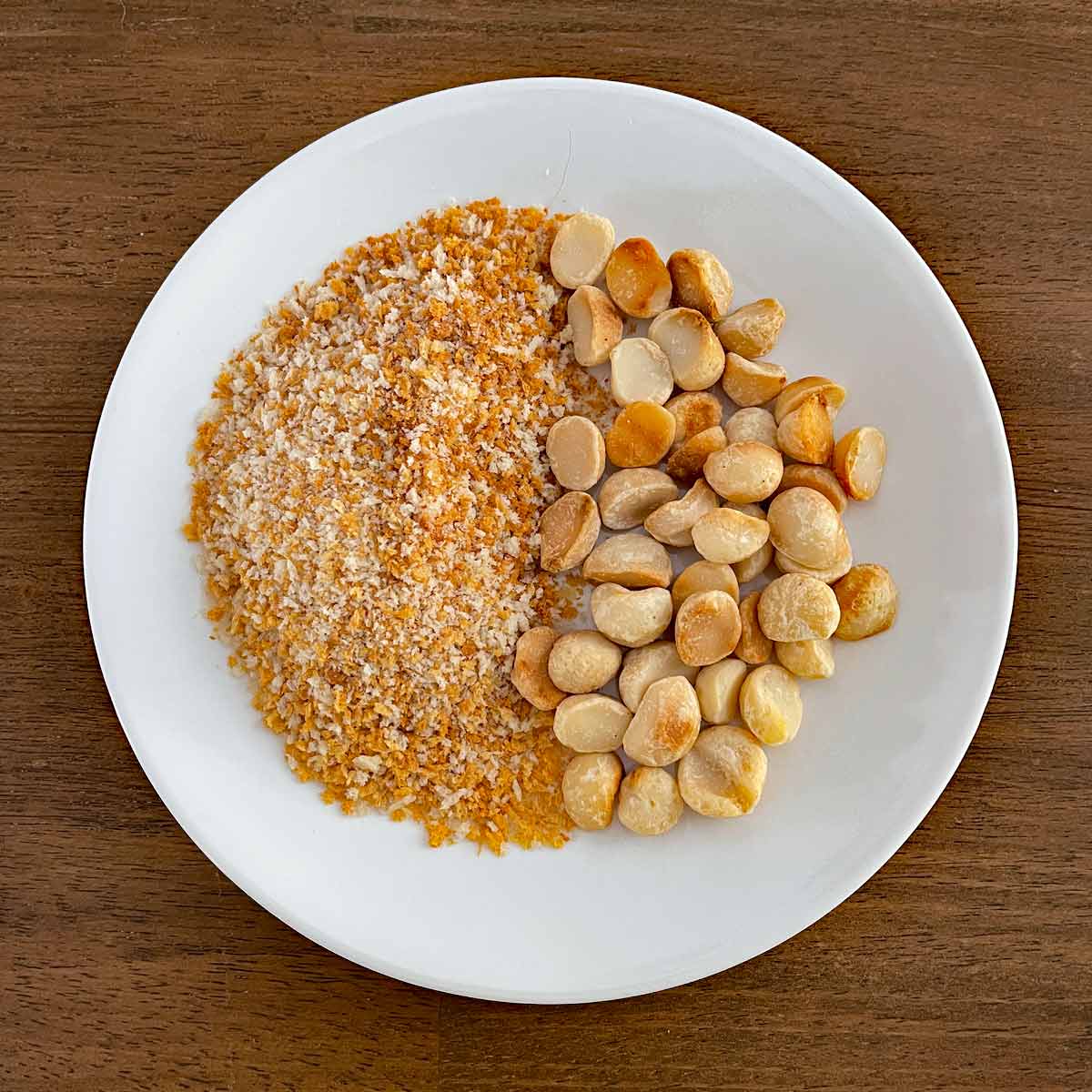 Plate with golden brown bread crumbs on one side and macadamia nuts on the other.