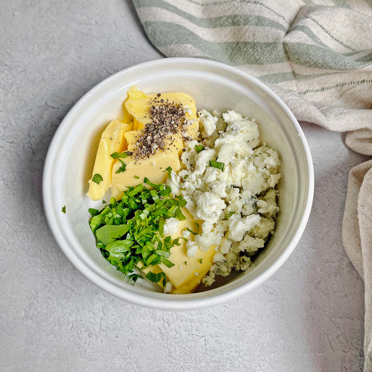 Small bowl with butter, Gorgonzola cheese, chopped parsley, and pepper.