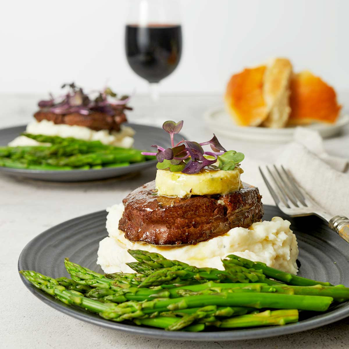 Plate with steak over mashed potatoes with a pat of Gorgonzola placed on top.