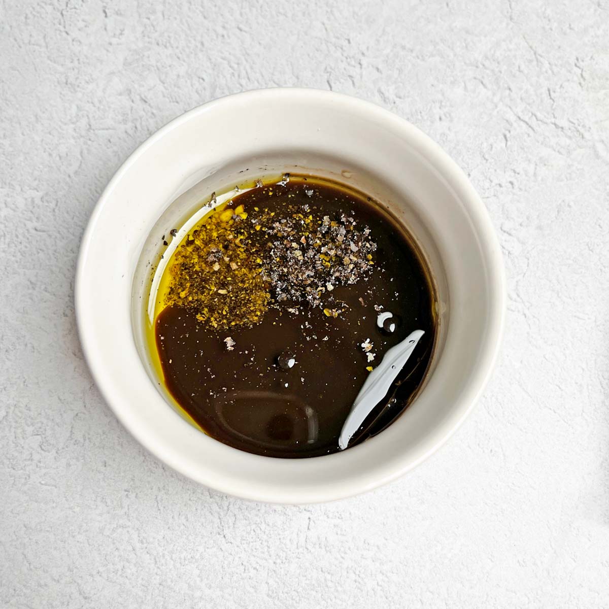 Small bowl with olive oil, Worcestershire sauce, and pepper.