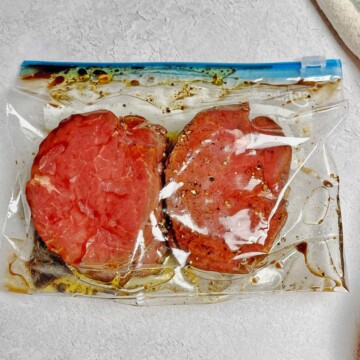 Plastic zip-top bag with 2 steaks and marinade.