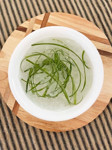 Green onions soaking in a bowl of ice water.