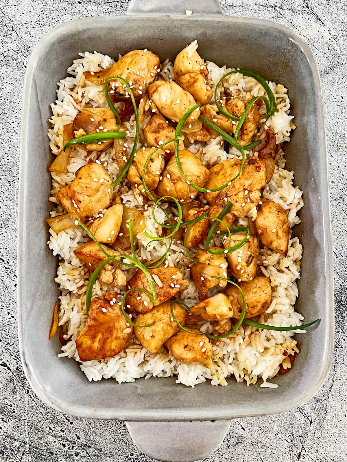 Casserole dish with chicken and sauce on top of rice.