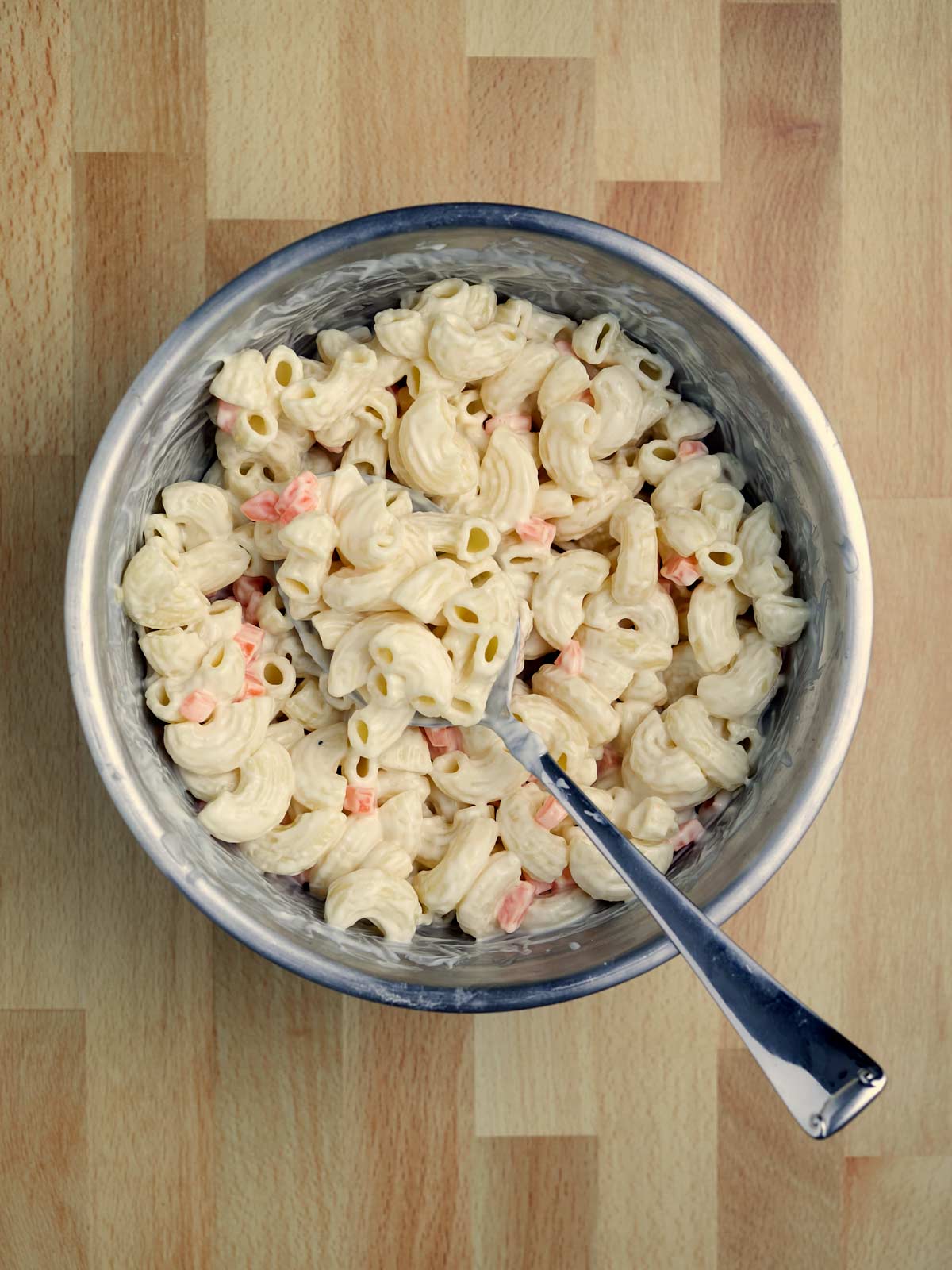A bowl of Hawaiian Style Macaroni Salad on a wooden table.