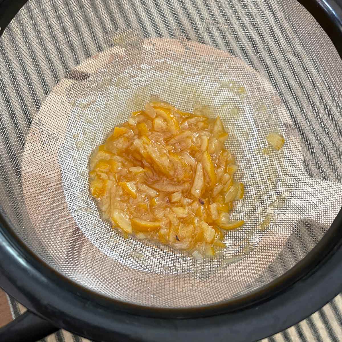 The marmalade is poured through a sieve catching the liquid in a bowl.
