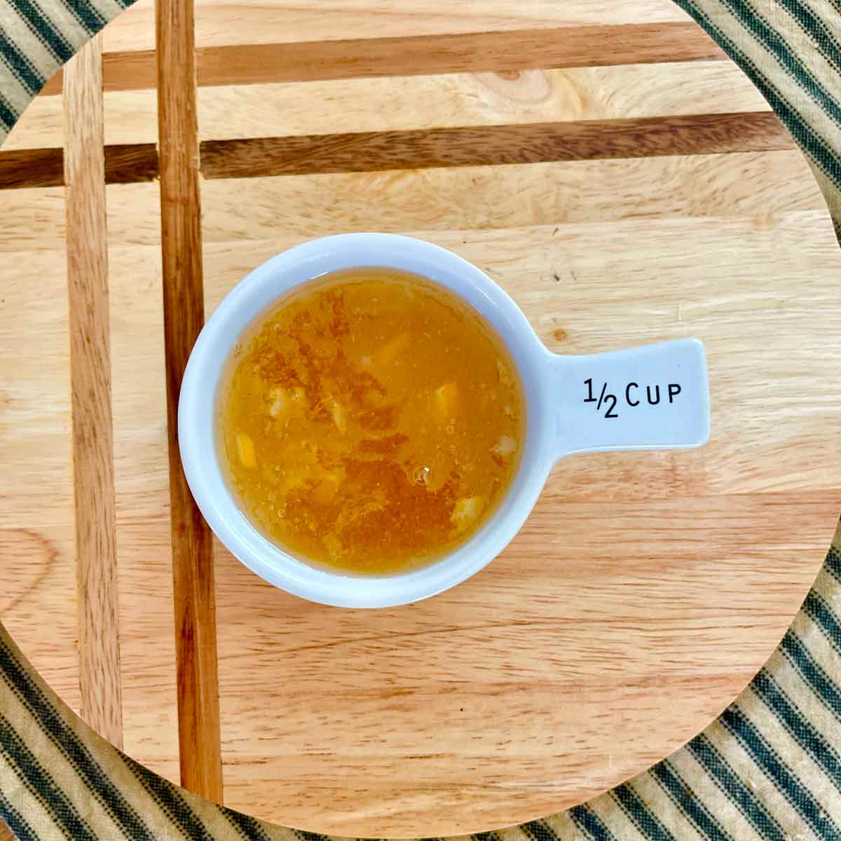 The cool thickened marmalade is in a ½ cup measuring cup.