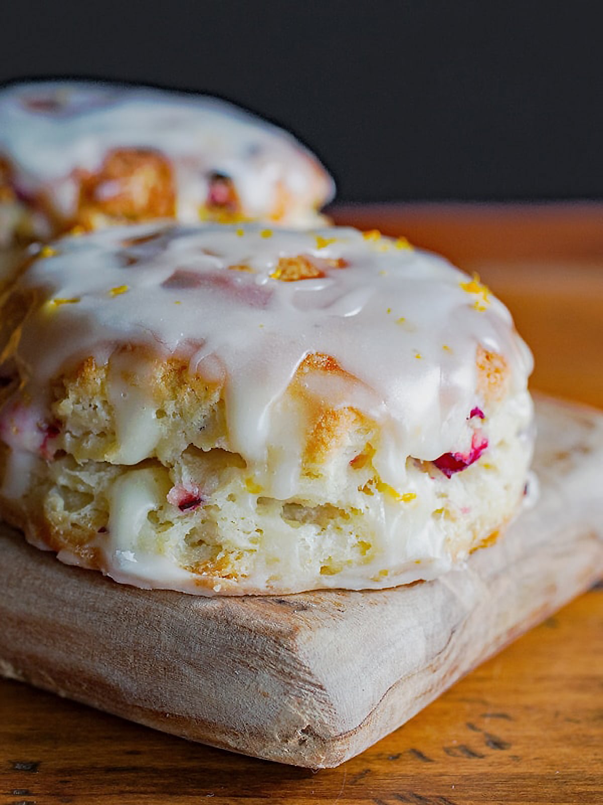 Round scone with white glaze and cranberry bits in the batter.