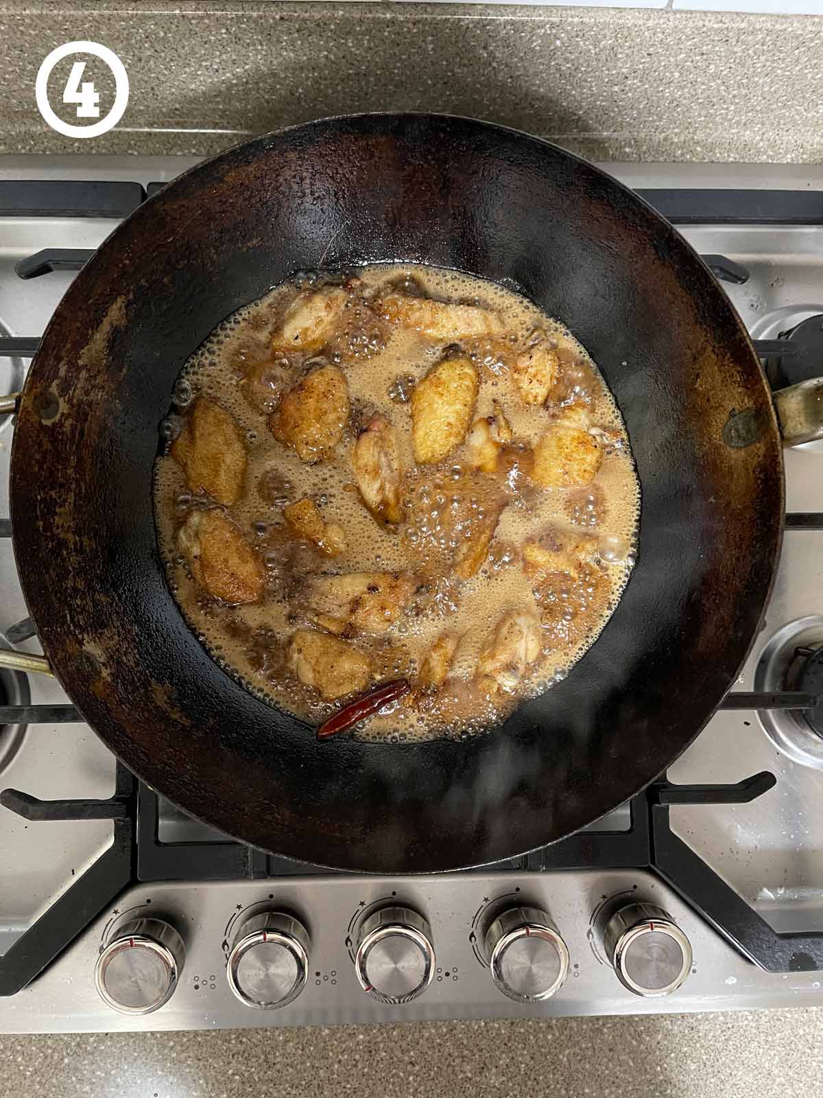 Grandmother's Chinese chicken wings frying in a wok on a stove top.