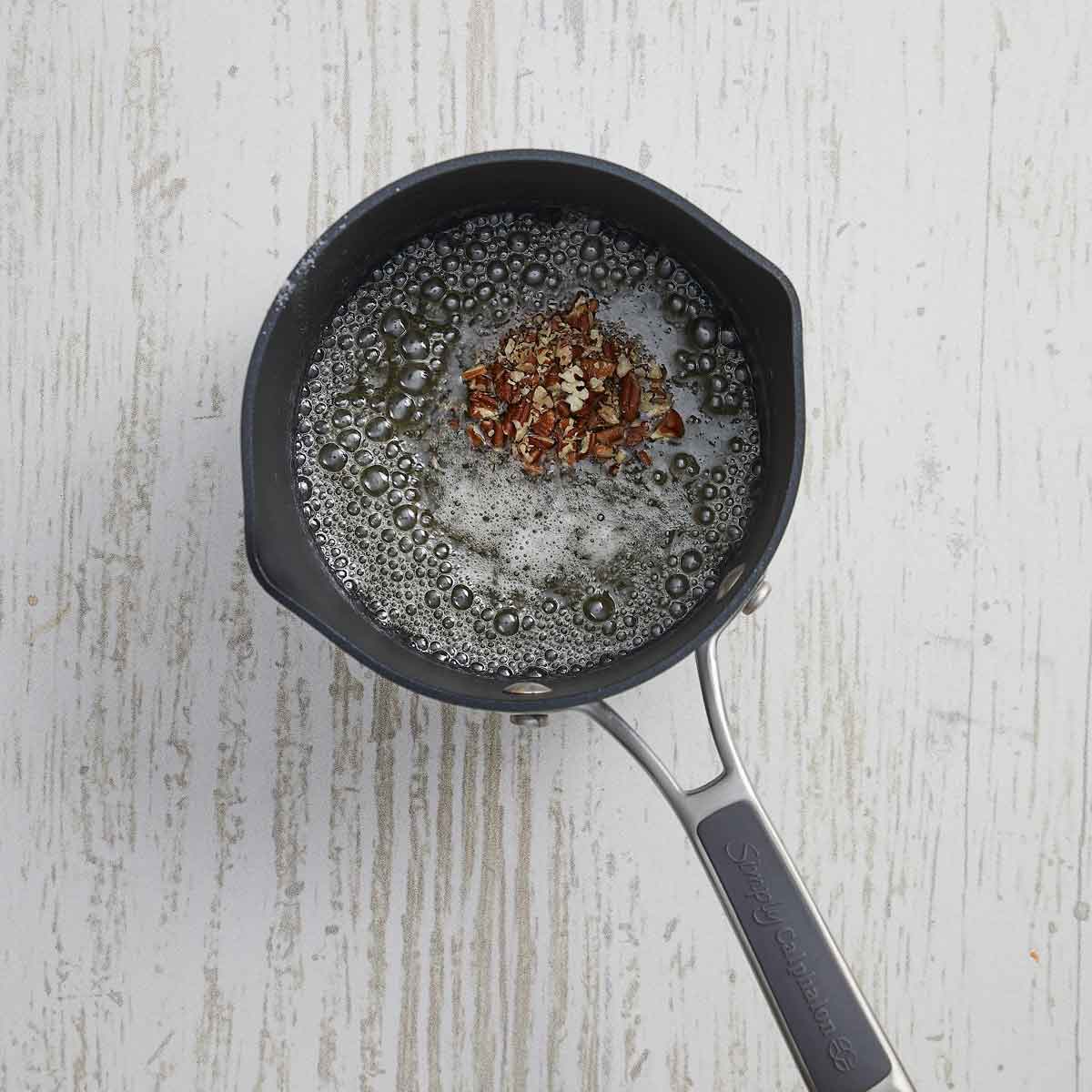 The sugar mixture is bubbling hot and pecans are added.