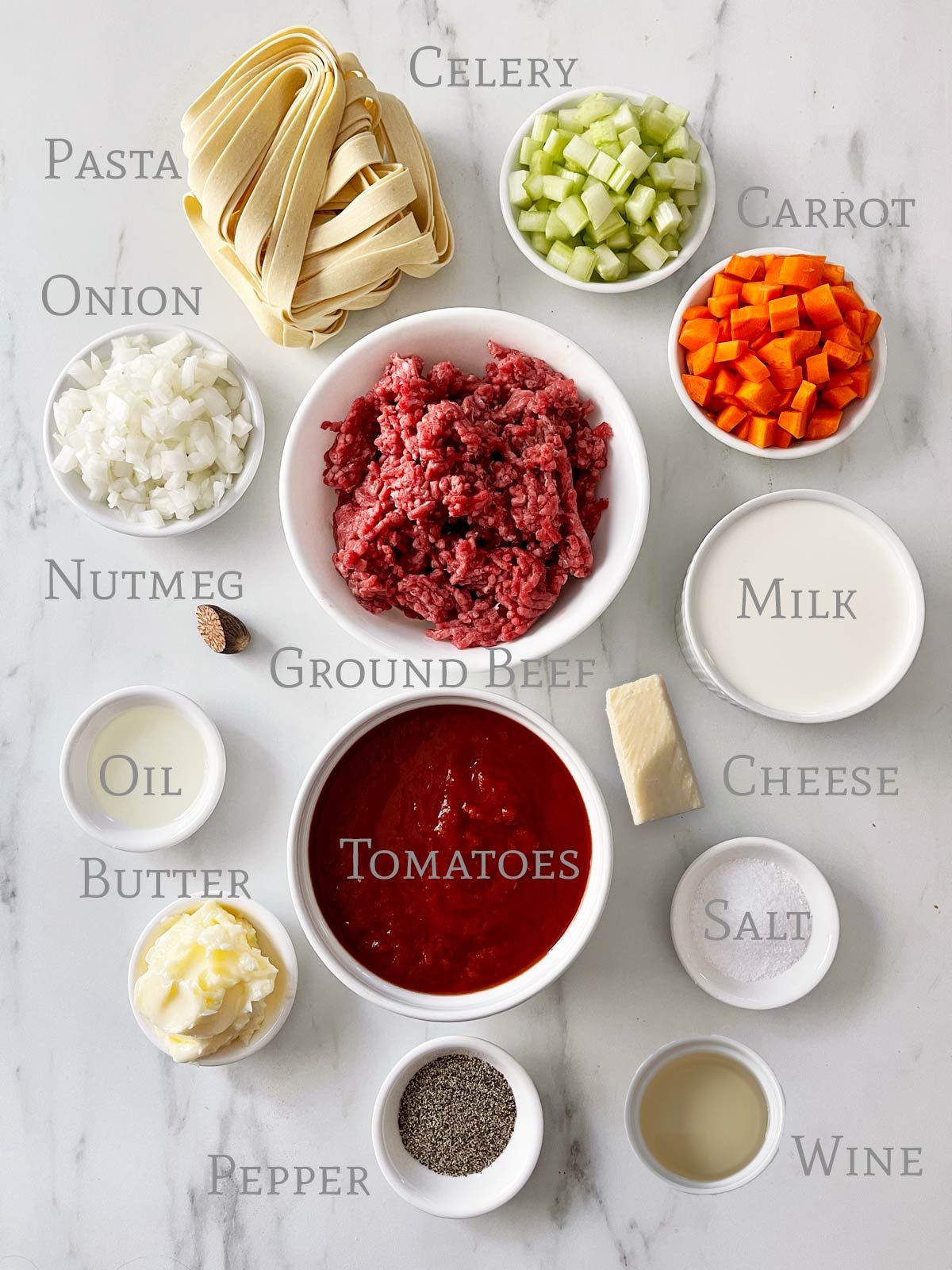 Ingredients for bolognese on marble surface.