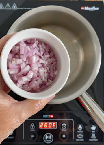 Shallots being added to a small saucepan.
