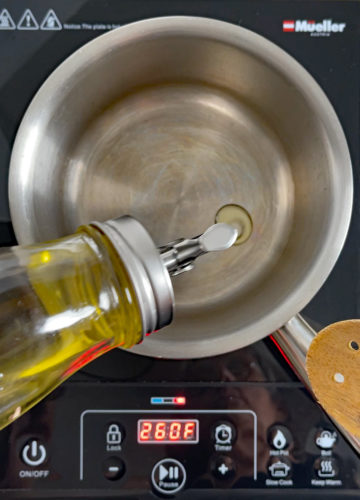 Olive oil being poured into a small saucepan.