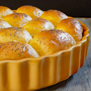 A yellow baking dish with squash dinner rolls.