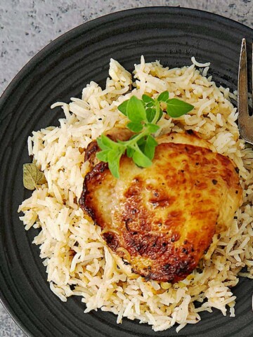 Greek chicken thigh with rice and fresh oregano.