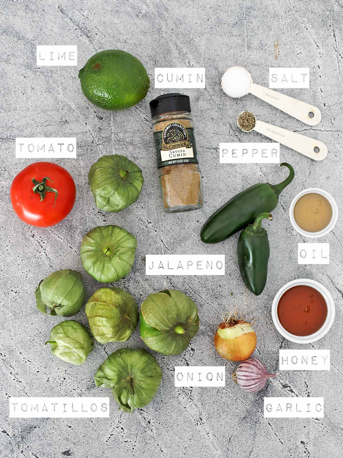 All the ingredients to make Chipotle Style Green Chili Salsa Recipe on a cement countertop.