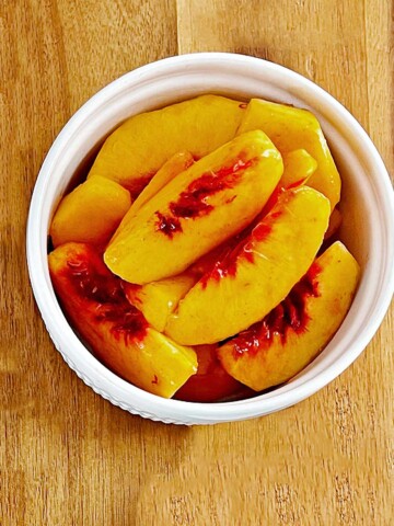 Bowl of sliced peaches with lemon juice.